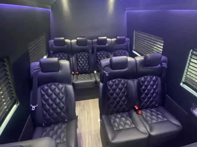 Executive Sprinter with quilted black leather seating, a clear center aisle and violet ceiling lighting — NYC airport transfers