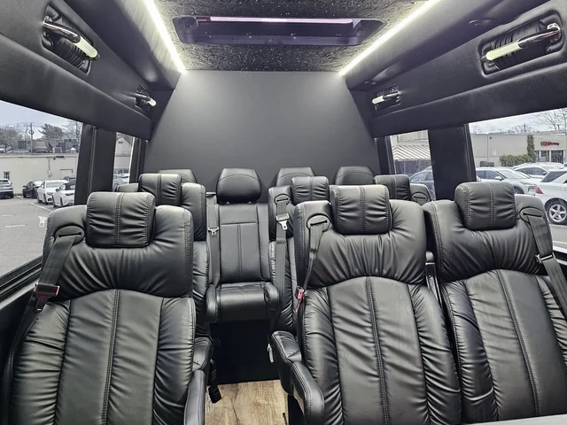 Executive Sprinter with forward-facing black leather seats, a table and white ceiling light strips — Corporate Transportation New Jersey — Mercedes Sprinter