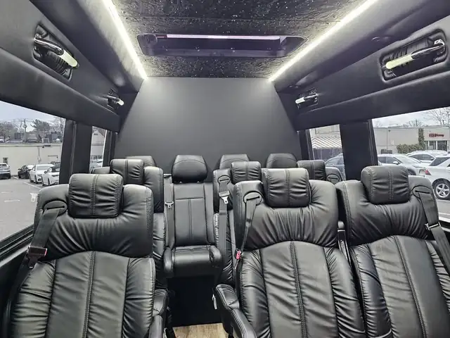 Executive Sprinter passenger rows of black leather seats under a dark starlit ceiling — Sprinter service in Williamsburg