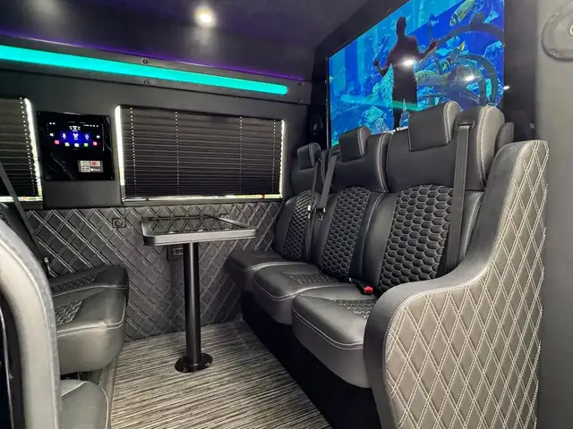 Executive Sprinter side-facing leather seats with a standing table, teal LED and an ocean-scene TV screen — Sprinter service in The Hamptons