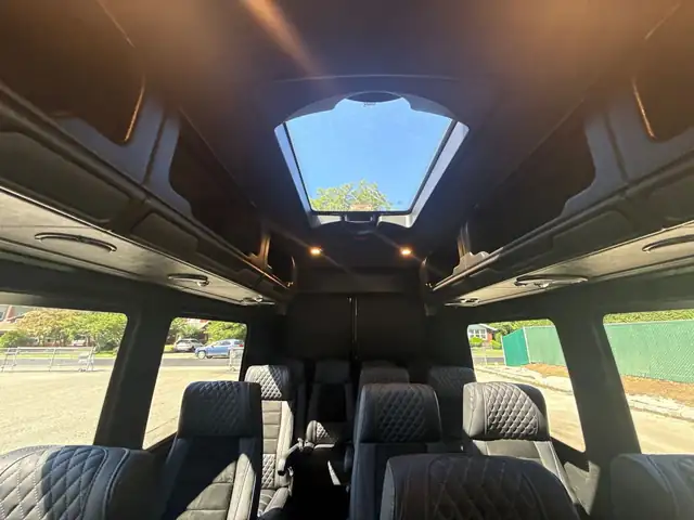 Executive Sprinter cabin with a glass skylight overhead and black leather seating — Van for Hire NYC: 12–15 Passenger Mercedes Sprinter