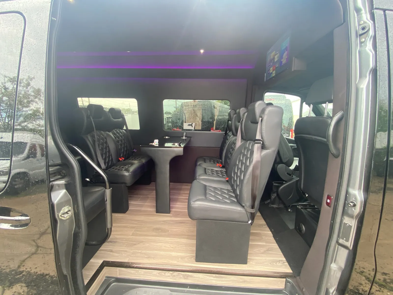 Executive Sprinter interior seen through the open door, with leather seating and a purple ceiling glow — New Jersey Sprinter service
