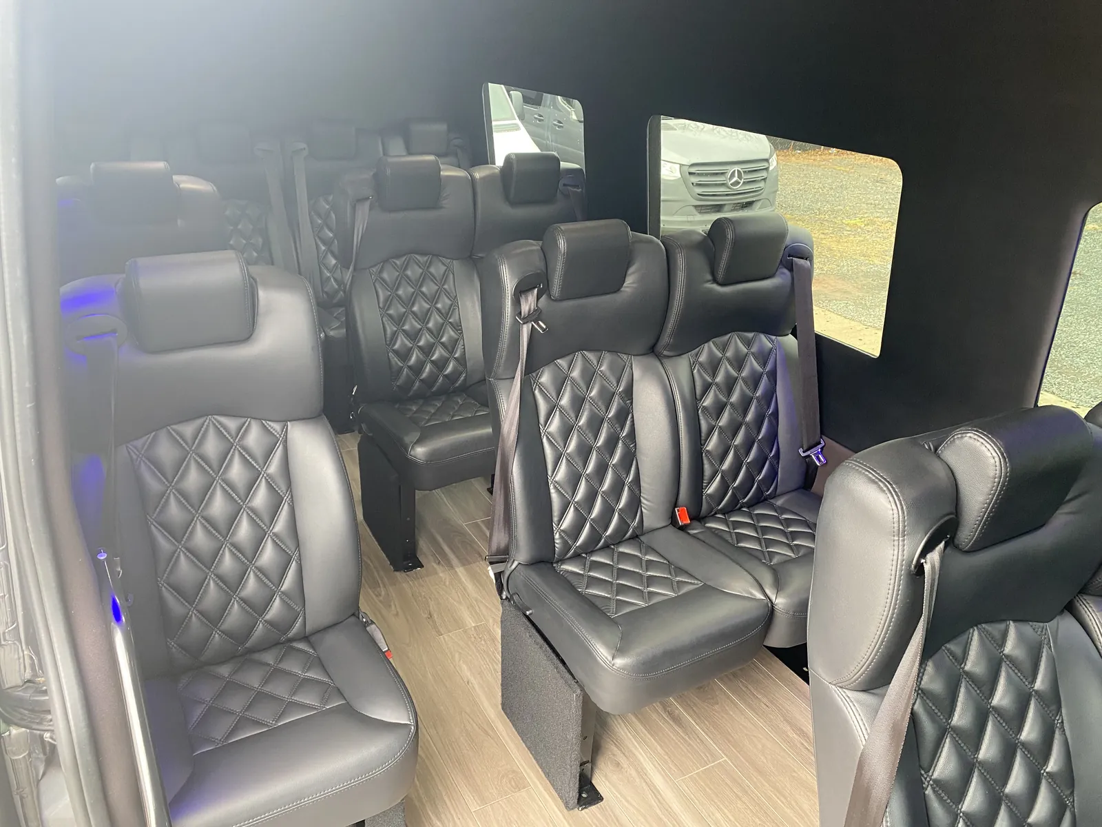 Executive Sprinter diamond-stitched black leather seats with seatbelts and a bright, wide window view — MetLife Stadium & Event Shuttle