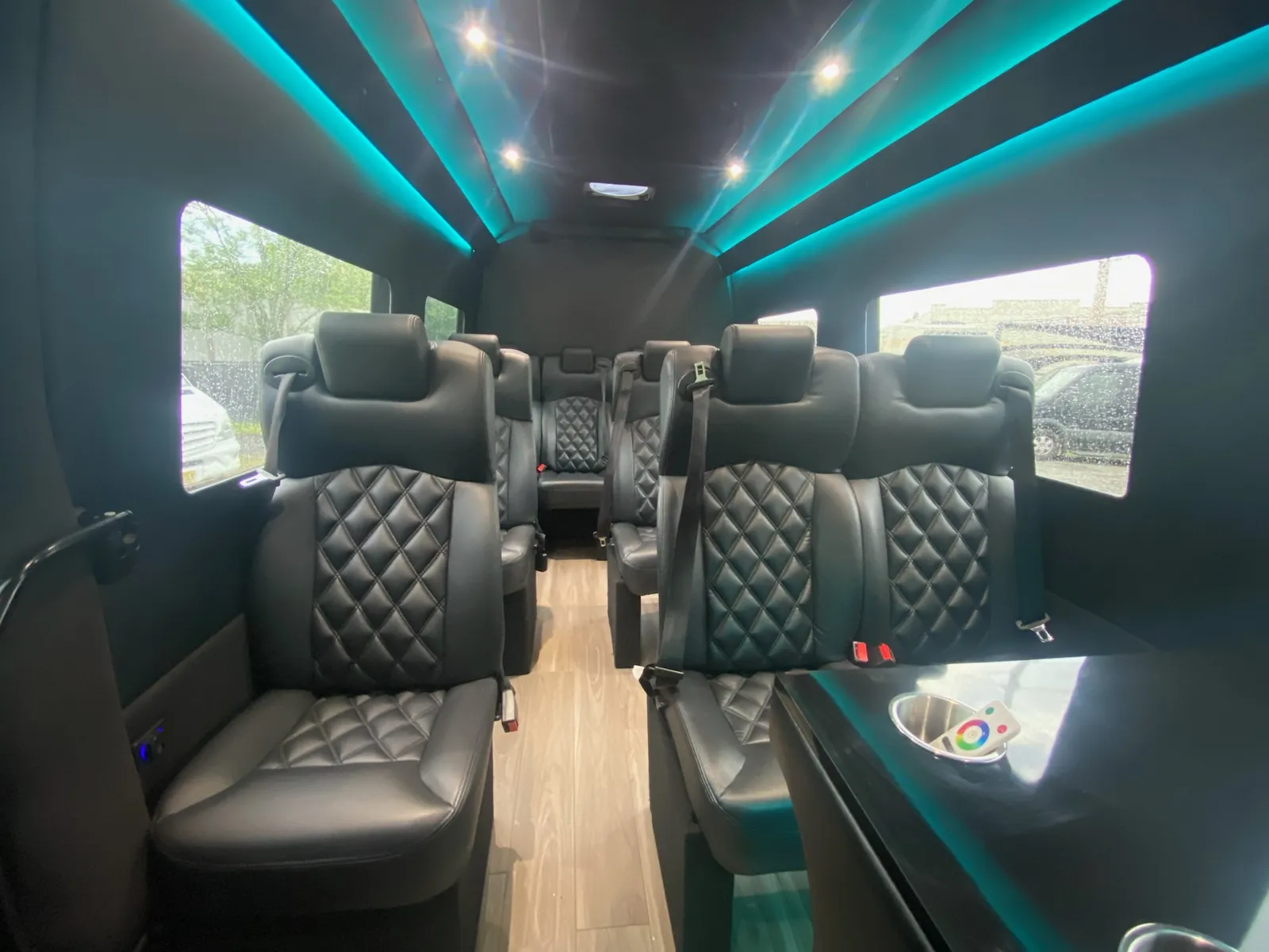 Executive Sprinter with teal LED ceiling lines and quilted black leather seats beside large windows — Corporate Shuttle