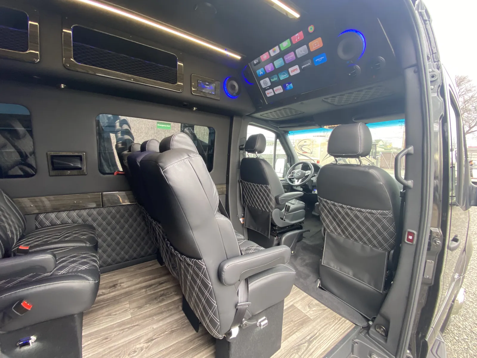 Executive Sprinter cabin through the side door, showing leather captain seats and a ceiling entertainment panel — Van for Hire NYC: 12–15 Passenger Mercedes Sprinter