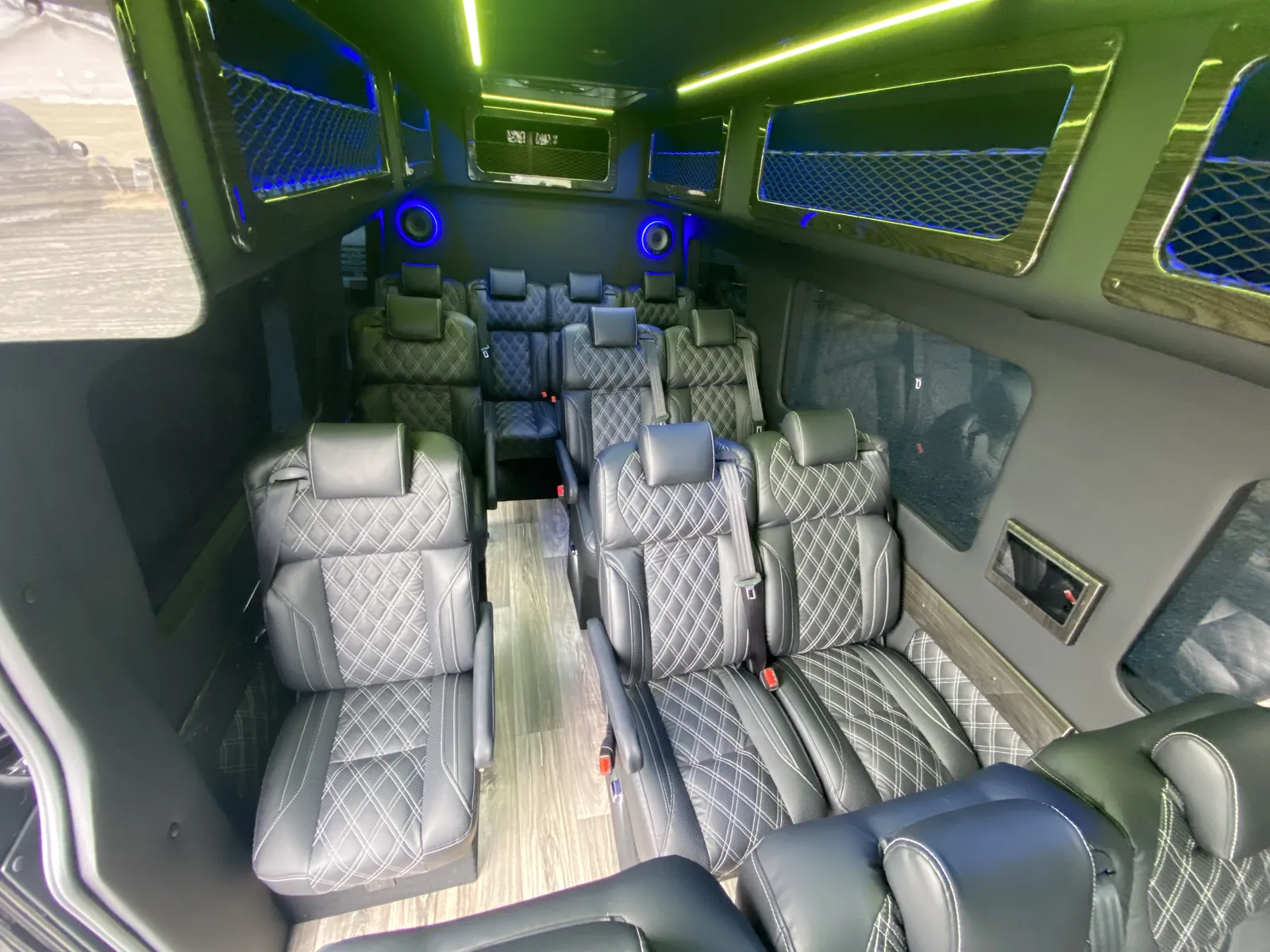 Executive Sprinter aisle lined with gray leather seats, green ceiling light and mesh window shades — Sprinter service in Williamsburg
