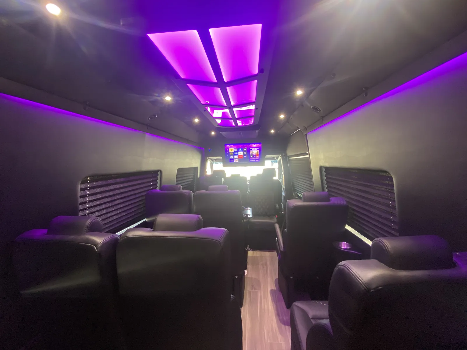 Executive Sprinter cabin with a bright purple ceiling panel and dark leather seats facing forward — Corporate Transportation New Jersey — Mercedes Sprinter
