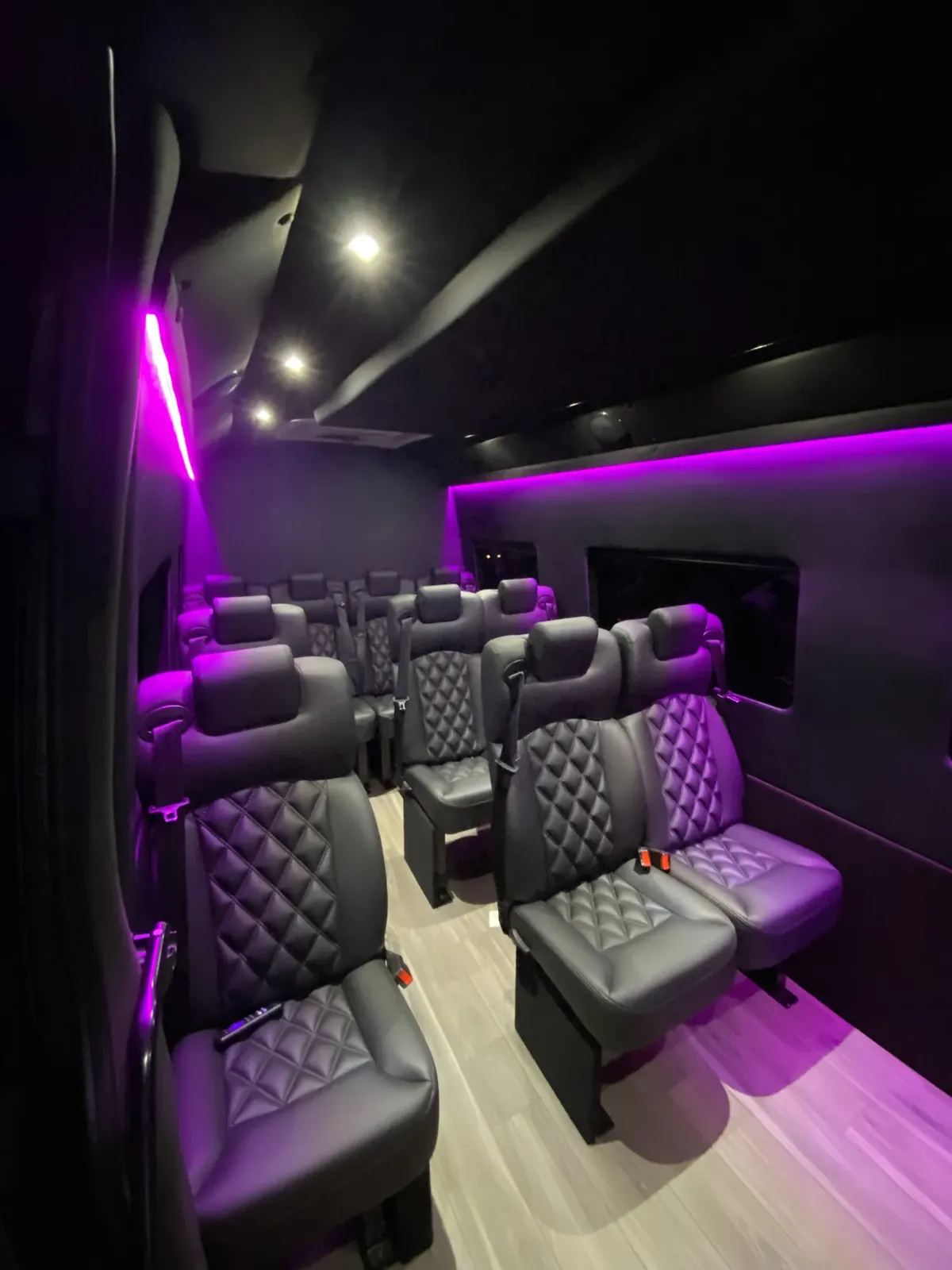 Executive Sprinter with magenta side lighting, rows of leather seats and a wood-look floor — Sprinter service in Tribeca