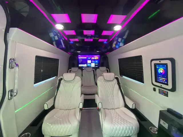 Jet Sprinter with facing white leather captain chairs, a TV and a magenta panel ceiling — Shuttle Service Long Island — Mercedes Sprinter