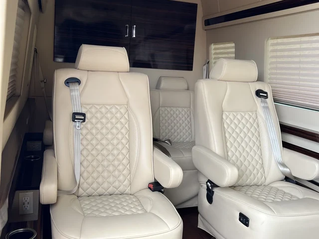 Jet Sprinter with two cream diamond-stitched leather recliners, black side tables and a wall-mounted TV, Mercedes Sprinter NYC