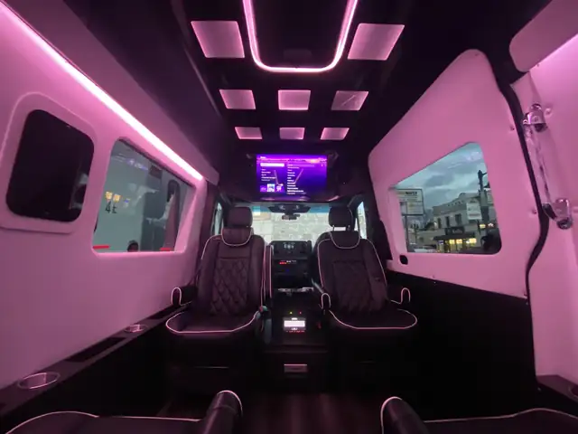Jet Sprinter with pink cabin lighting, black leather captain chairs and a TV at the front — Sprinter service in Financial District