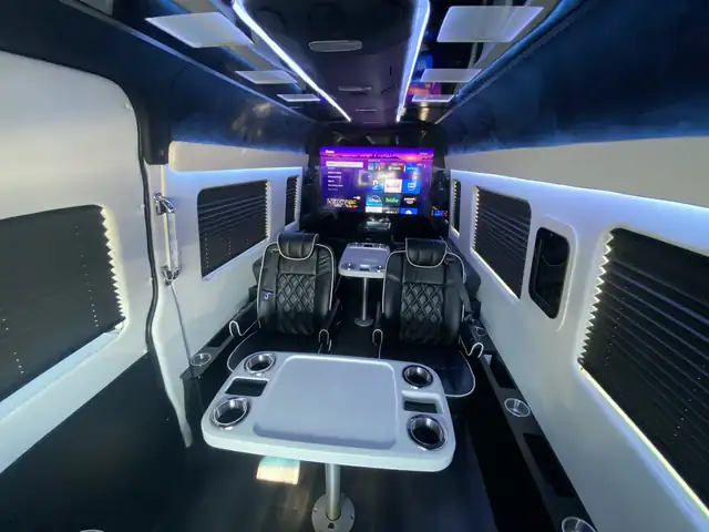 Jet Sprinter with a TV, black leather chairs and a white round table with cup holders — Manhattan to North Fork Wineries (Long Island) transfers