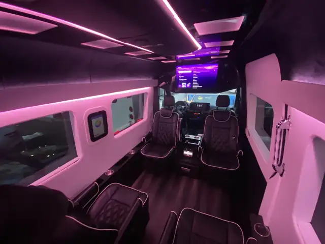 Jet Sprinter with pink ambient lighting, leather chairs and a TV toward the front — Sprinter service in Tribeca