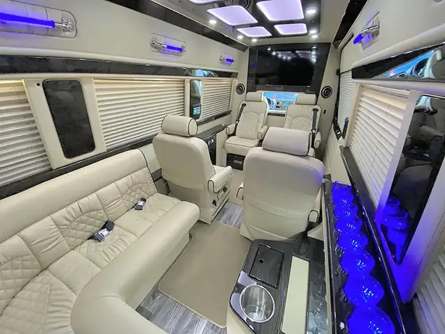 Jet Sprinter with a cream leather L-shaped sofa, captain chairs and blue underlighting — EWR airport group transfers