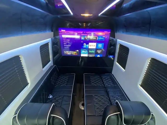 Jet Sprinter with facing black leather benches, a large TV and white-lit ceiling curves — Wine Tours