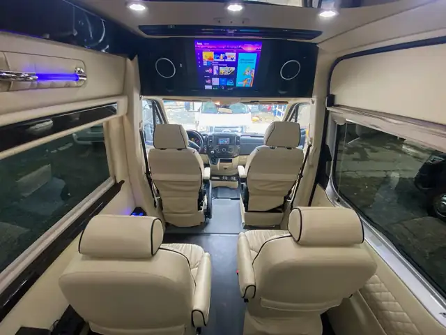 Jet Sprinter with cream leather captain chairs, a front TV and blue ceiling accents — Group Transportation