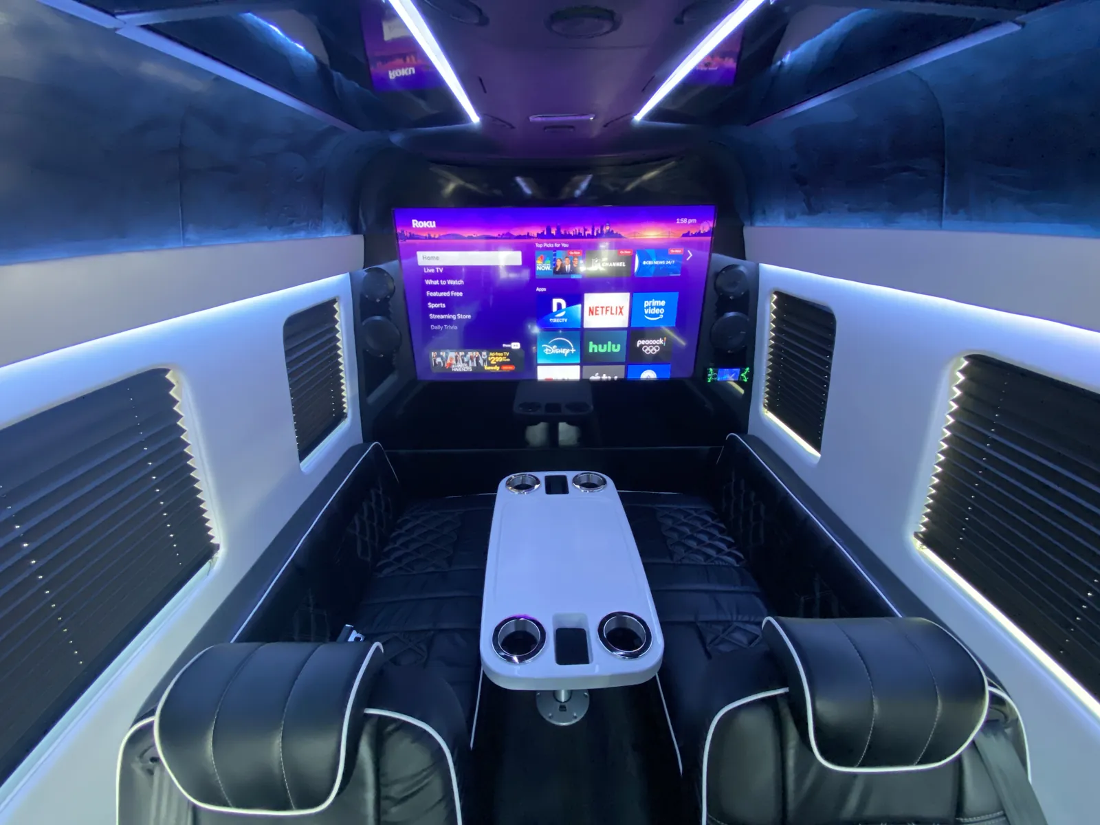 Jet Sprinter looking toward a large front TV with a white center table and black leather seats — Jet Sprinter NYC