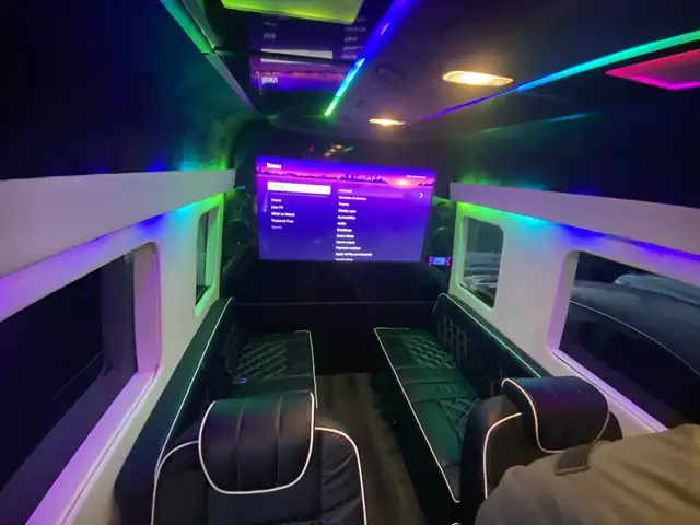Jet Sprinter with green and purple accent lighting, black side benches and a large TV — Luxury Van Rental — Mercedes Sprinter