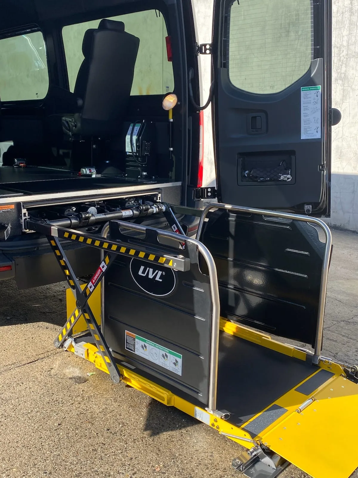 Wheelchair accessible Sprinter side lift with yellow safety edge stowed beside a fold-up seat — Wheelchair Accessible Van NYC — Mercedes Sprinter