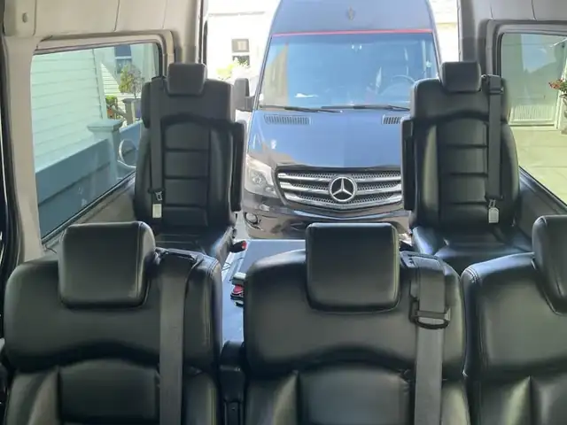 Wheelchair accessible Sprinter looking rearward over black leather seat backs to a parked van — Wheelchair Accessible Van NYC — Mercedes Sprinter