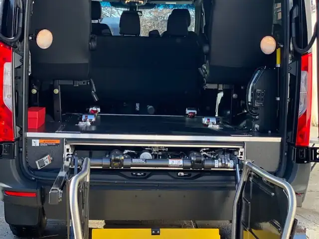 Wheelchair accessible Sprinter rear lift raised at the doors with a yellow safety plate and folding seats — Wheelchair Accessible Van NYC — Mercedes Sprinter